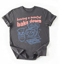 Flat lay of a Having a Mental Bake Down baking shirt with mixer graphic on brown t-shirt on a ivory background