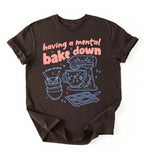 Flat lay of a Having a Mental Bake Down baking shirt with mixer graphic on brown t-shirt on a white background