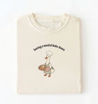 Flat lay of a cream Funny Having a Mental Bake Down shirt with baker goose holding artisan bread graphic on a white background 