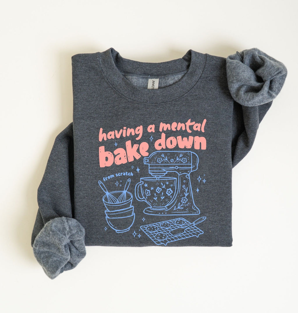 Flat lay of a dark heather Funny Having a Mental Bake Down baking sweatshirt with mixer and baking tools graphic on a white background 