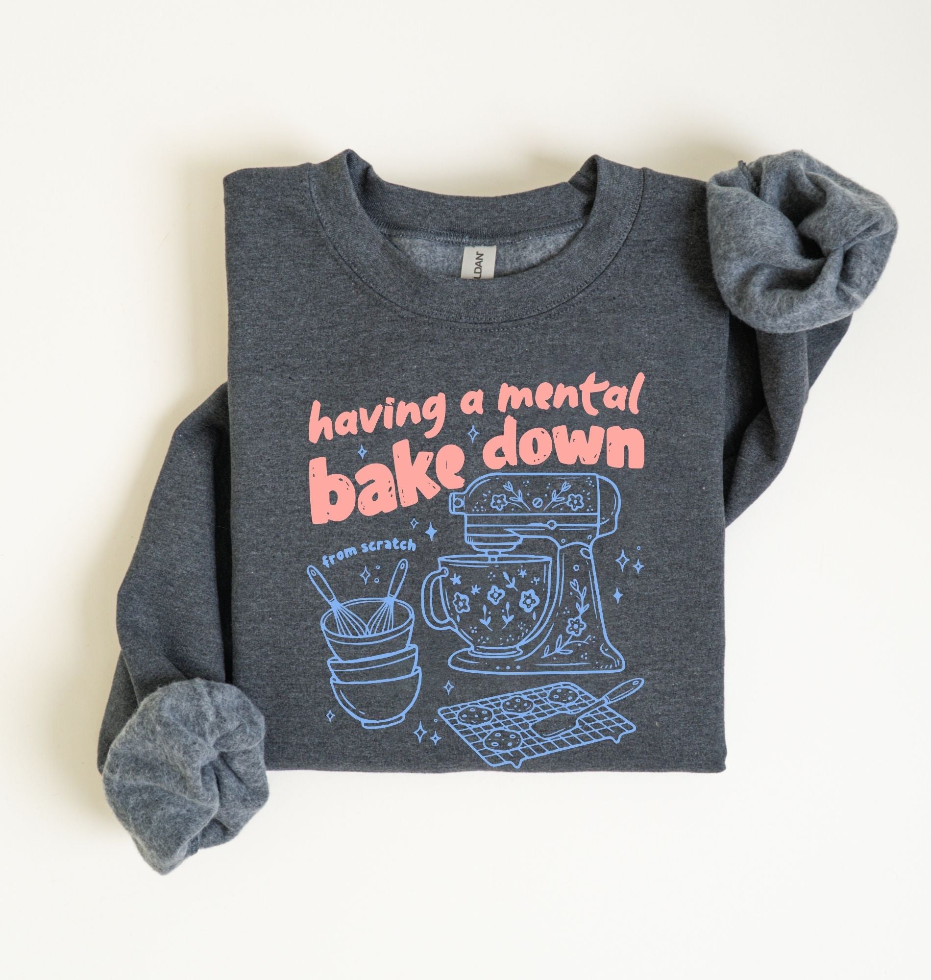 Flat lay of a dark heather Funny Having a Mental Bake Down baking sweatshirt with mixer and baking tools graphic on a white background 