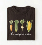 Flat lay of a dark chocolate homegrown vegetable t shirt with illustrated carrot celery turnip and corn gardener gift on a white background