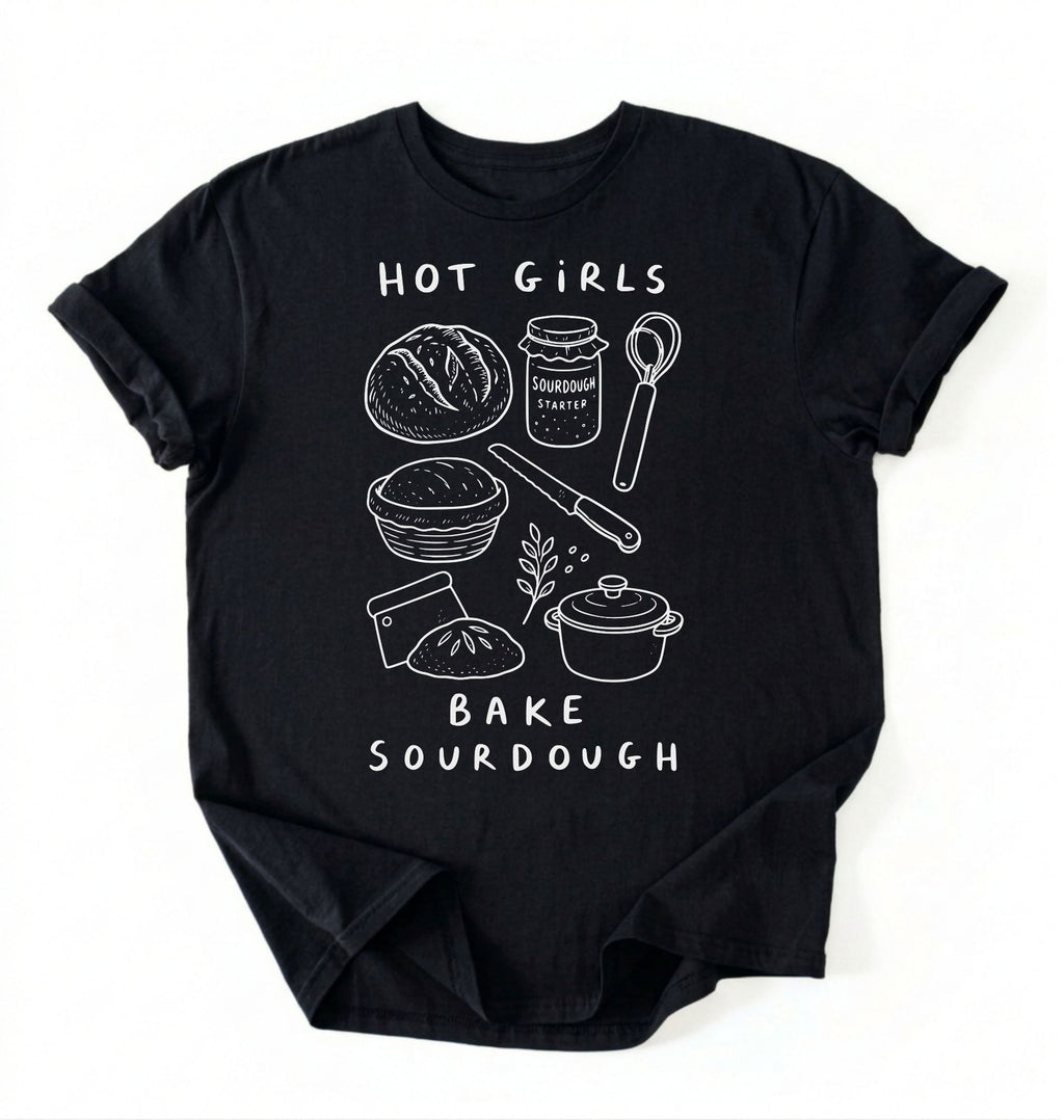 Flat lay of a Funny hot girls bake sourdough shirt with bread and baking tools illustration on black tee on a white background 