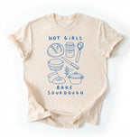 Flat lay of a Funny hot girls bake sourdough shirt with bread and baking tools illustration on cream tee on a white background 