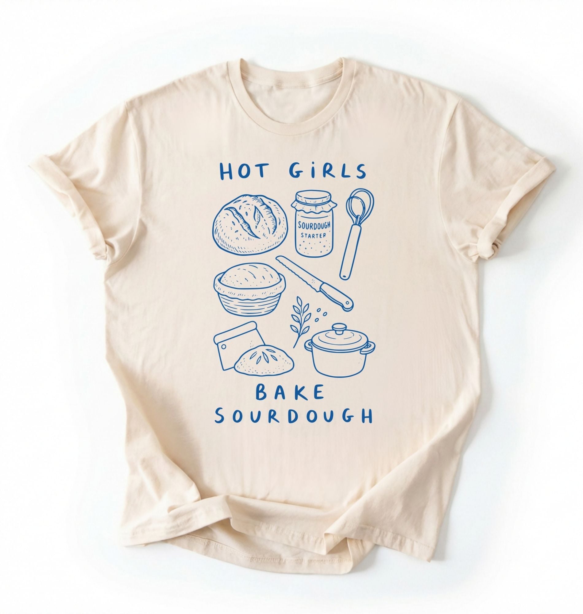 Flat lay of a Funny hot girls bake sourdough shirt with bread and baking tools illustration on cream tee on a white background 