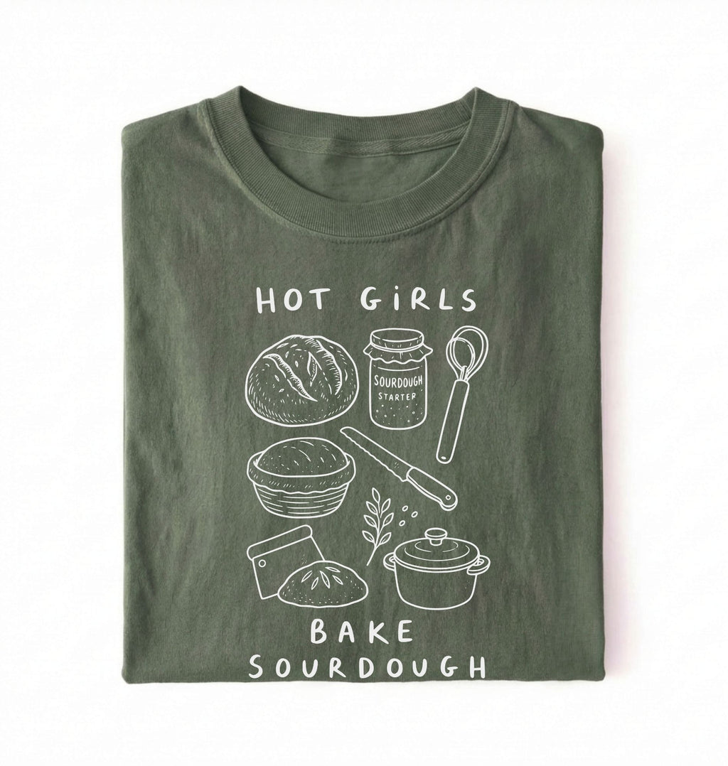 Flat lay of a Funny hot girls bake sourdough shirt with bread and baking tools illustration on green tee on a white background 