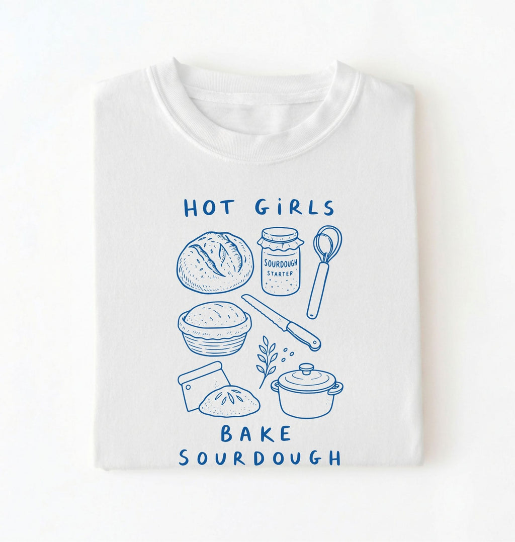 Flat lay of a Funny hot girls bake sourdough shirt with bread and baking tools illustration on white tee on a white background 