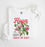 Flat lay of a white crewneck sweatshirt displaying a detailed botanical illustration labeled “Hoya Wax Plant.