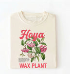 Flat lay of a ivory t-shirt featuring a detailed botanical illustration labeled “Hoya Wax Plant” with flowers and leaves.
