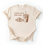 Flat lay of a Cute coffee and croissant shirt with cozy bakery aesthetic on black tee on a cream background 