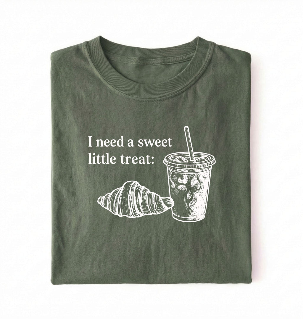 Flat lay of a Cute coffee and croissant shirt with cozy bakery aesthetic on black tee on a green background 