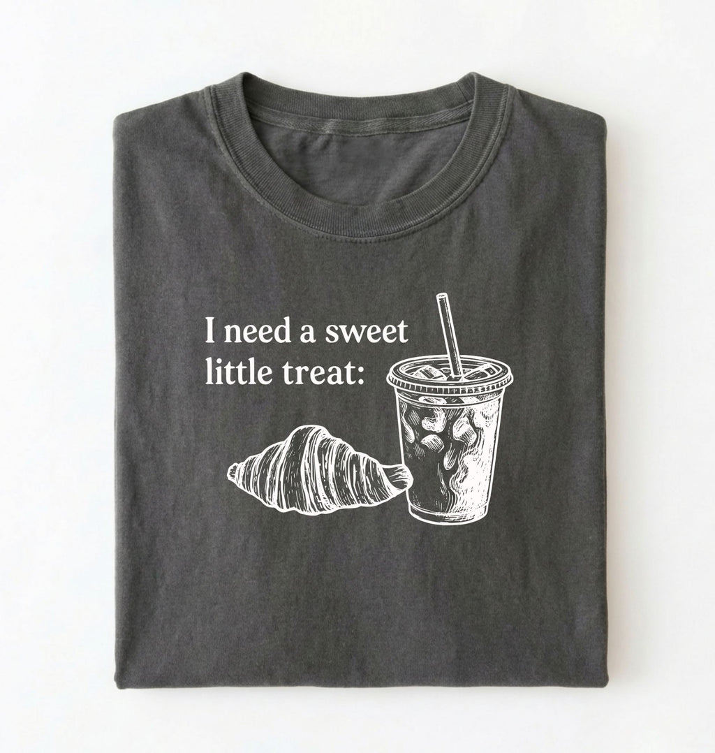 Flat lay of a Cute coffee and croissant shirt with cozy bakery aesthetic on pepper tee on a white background 