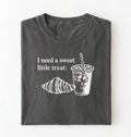 Flat lay of a Cute coffee and croissant shirt with cozy bakery aesthetic on pepper tee on a white background 