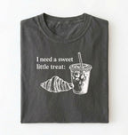 Flat lay of a Cute coffee and croissant shirt with cozy bakery aesthetic on pepper tee on a white background 