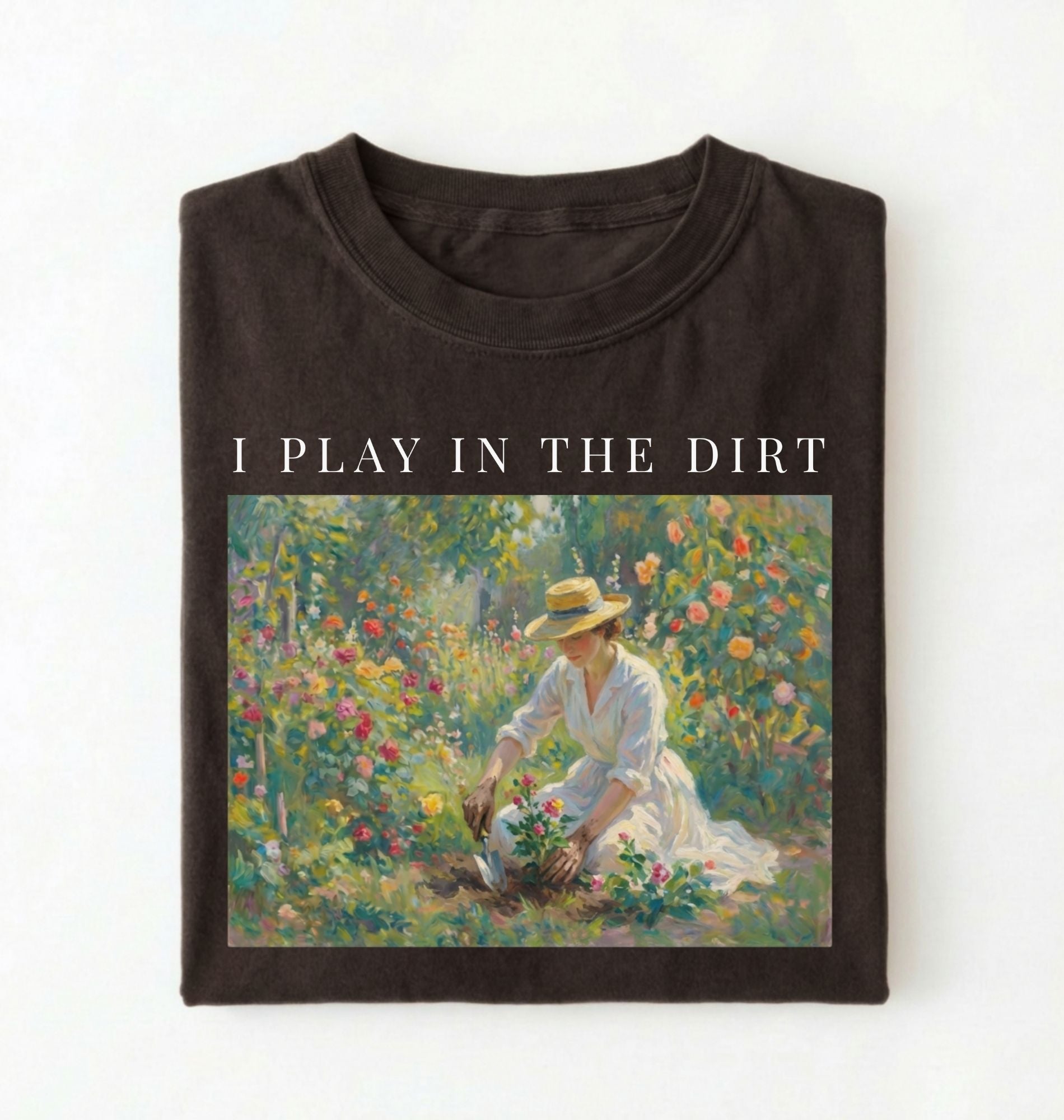 Flat lay of a dark brown chocolate t-shirt featuring a vintage-style garden painting with text reading “I Play In The Dirt.” On a white background 