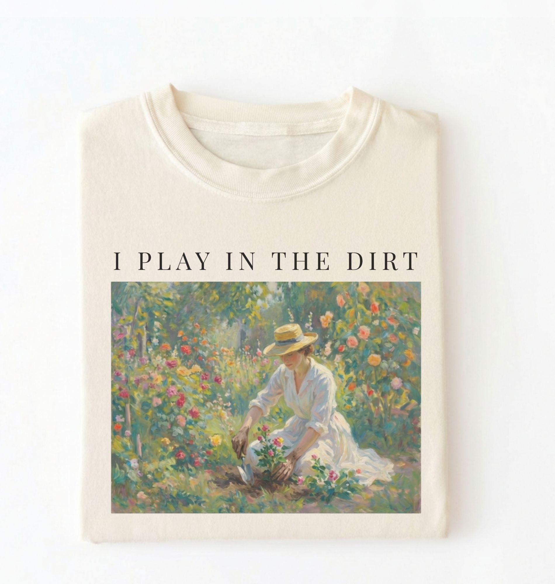 Flat lay of a natural t-shirt featuring a vintage-style garden painting with text reading “I Play In The Dirt.” On a white background 