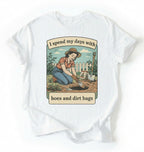 Flat lay of a white Funny gardening shirt with hoes and dirt bags text perfect for gardeners and plant lovers with humor on a white background 