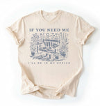 Flat lay of an ivory shirt written "If you need me I’ll be in my office gardening shirt with cottagecore bench and potted plants illustration on a white background 
