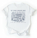 Flat lay of a white shirt written "If you need me I’ll be in my office gardening shirt with cottagecore bench and potted plants illustration on a white background 