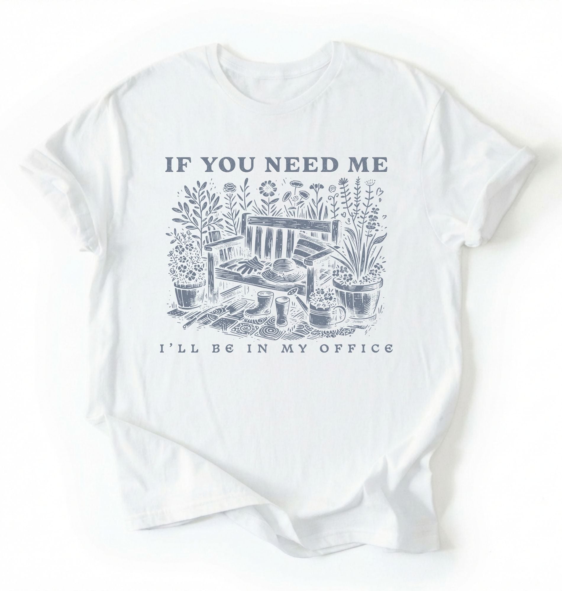 Flat lay of a white shirt written "If you need me I’ll be in my office gardening shirt with cottagecore bench and potted plants illustration on a white background 
