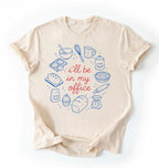 Flat lay of a Funny baking shirt with bread pie cupcake and baking tools illustration on cream tee on a white background 