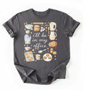 Flat lay of a charcoal Baking shirt with tools and desserts saying ill be in my office perfect gift for bakers and home baking lovers on a white background