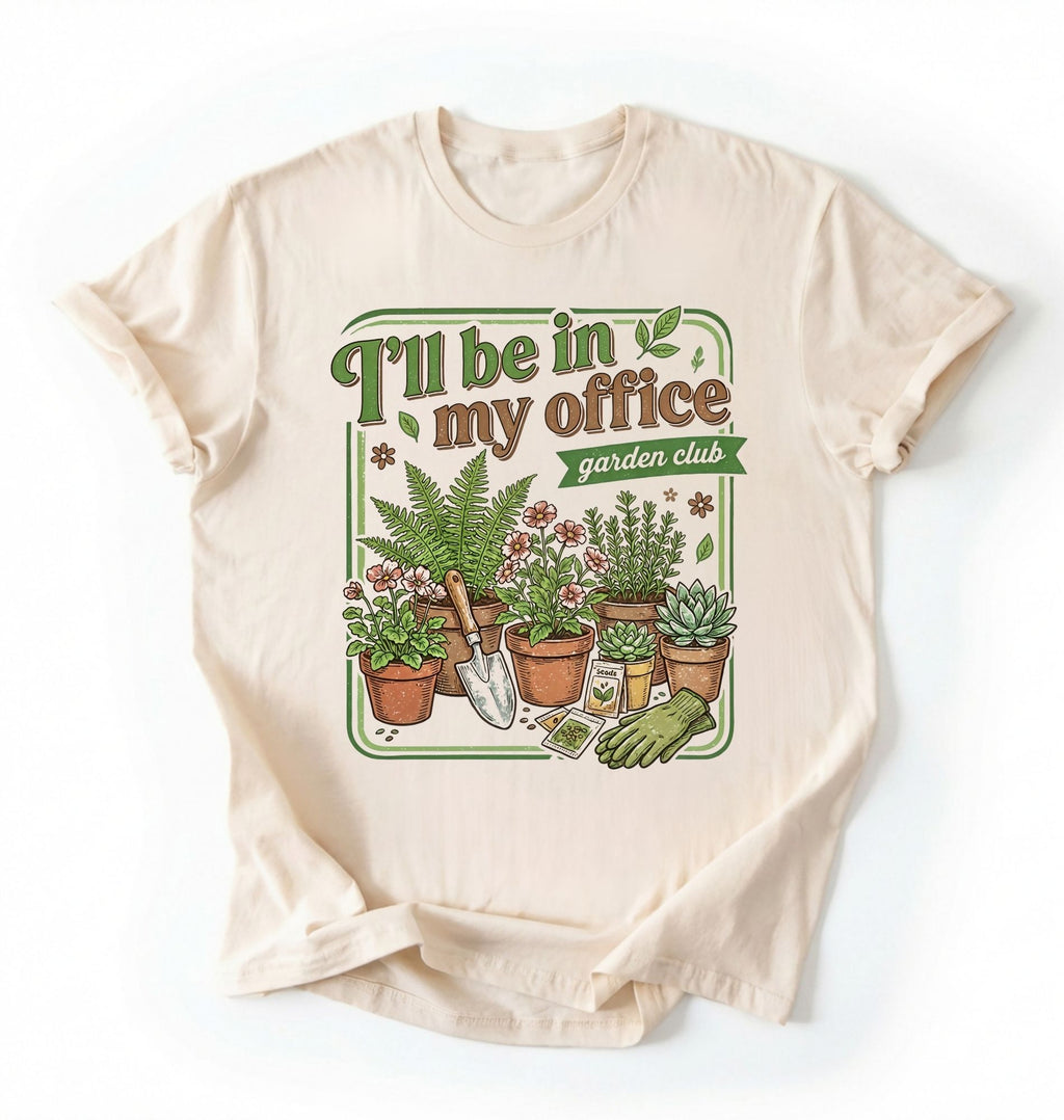 Flat lay of a Natural t-shirt featuring illustrated potted plants, tools, and text reading “I’ll Be In My Office Garden Club on a white background