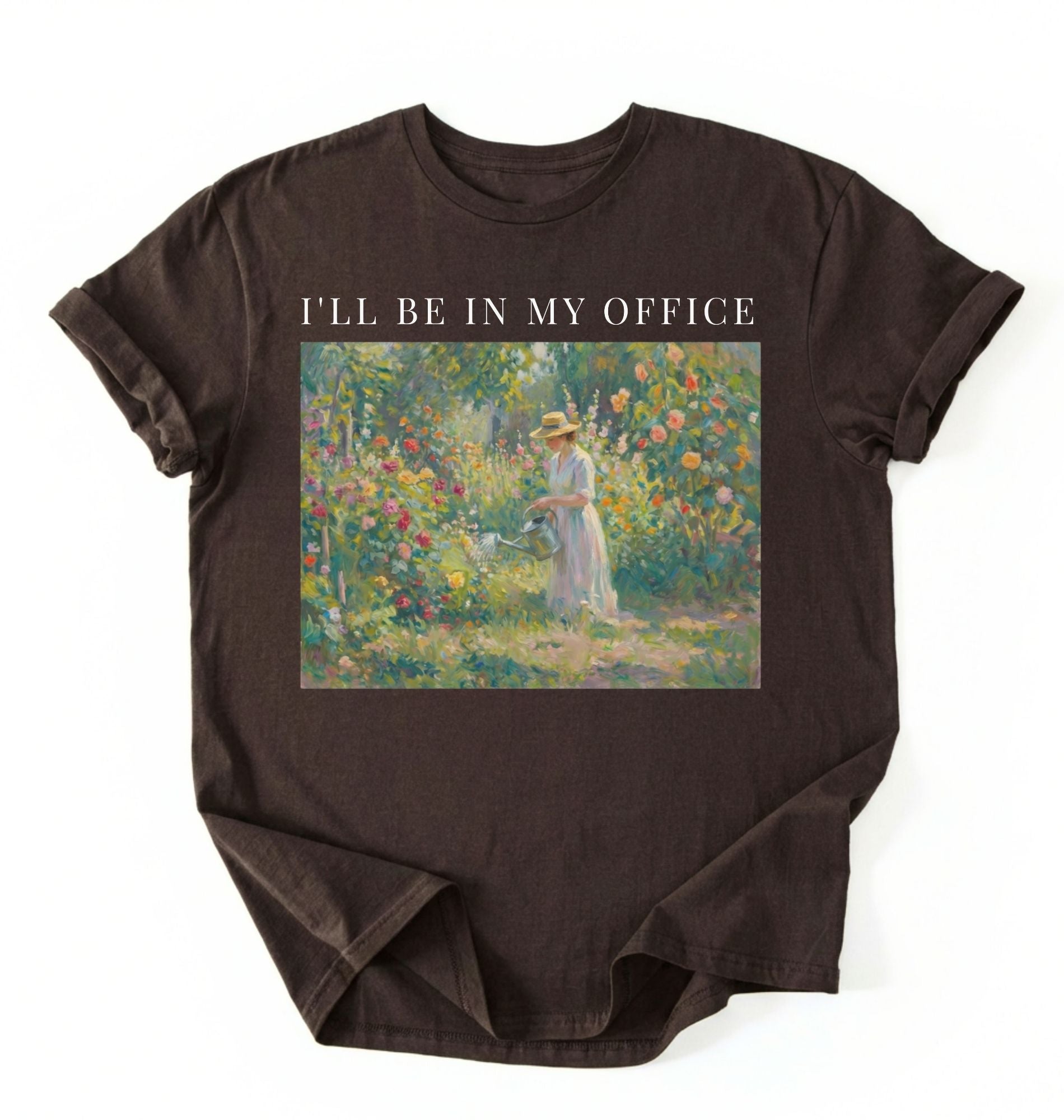Flat lay of a espresso t-shirt featuring a vintage garden painting of a woman tending flowers with text reading “I’ll Be In My Office.” On a white background 