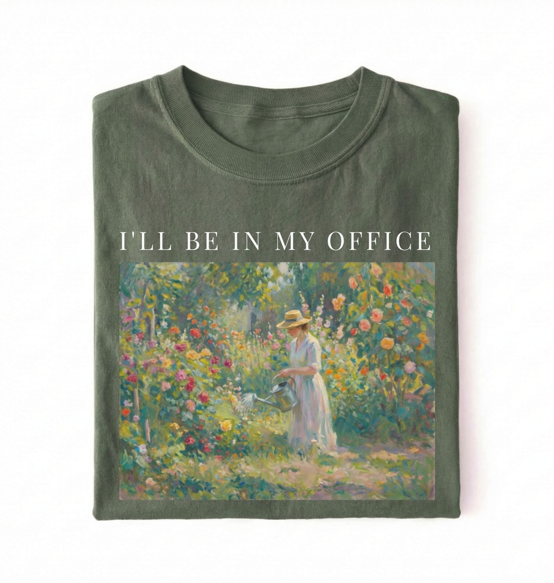 Flat lay of a moss t-shirt featuring a vintage garden painting of a woman tending flowers with text reading “I’ll Be In My Office.” On a white background 