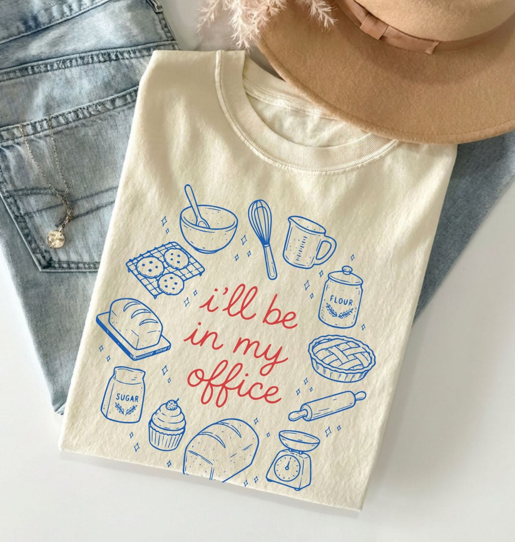 Beige t-shirt with baking-themed design and text 'I'll be in my office' on a light background.