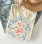 Beige t-shirt with baking-themed design and text 'I'll be in my office' on a light background.