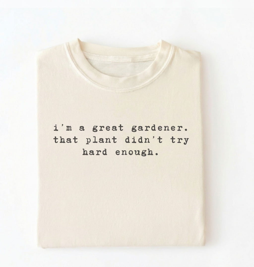 Flat lay of a ivory t-shirt featuring text reading “I’m a great gardener, that plant didn’t try hard enough.” Funny gardening shirt perfect for plant lovers, gardeners and houseplant owners on a white background