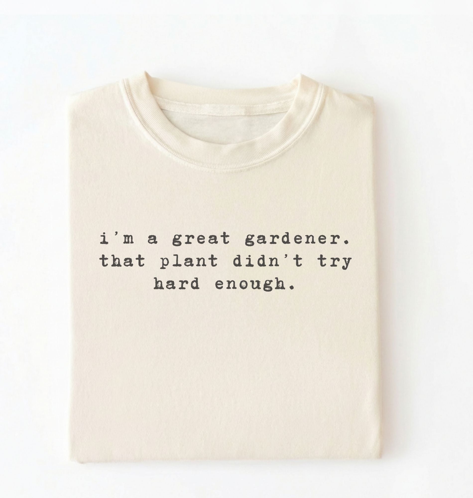 Flat lay of a ivory t-shirt featuring text reading “I’m a great gardener, that plant didn’t try hard enough.” Funny gardening shirt perfect for plant lovers, gardeners and houseplant owners on a white background