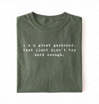 Flat lay of a dark green t-shirt featuring text reading “I’m a great gardener, that plant didn’t try hard enough.” Funny gardening shirt perfect for plant lovers, gardeners and houseplant owners on a white background