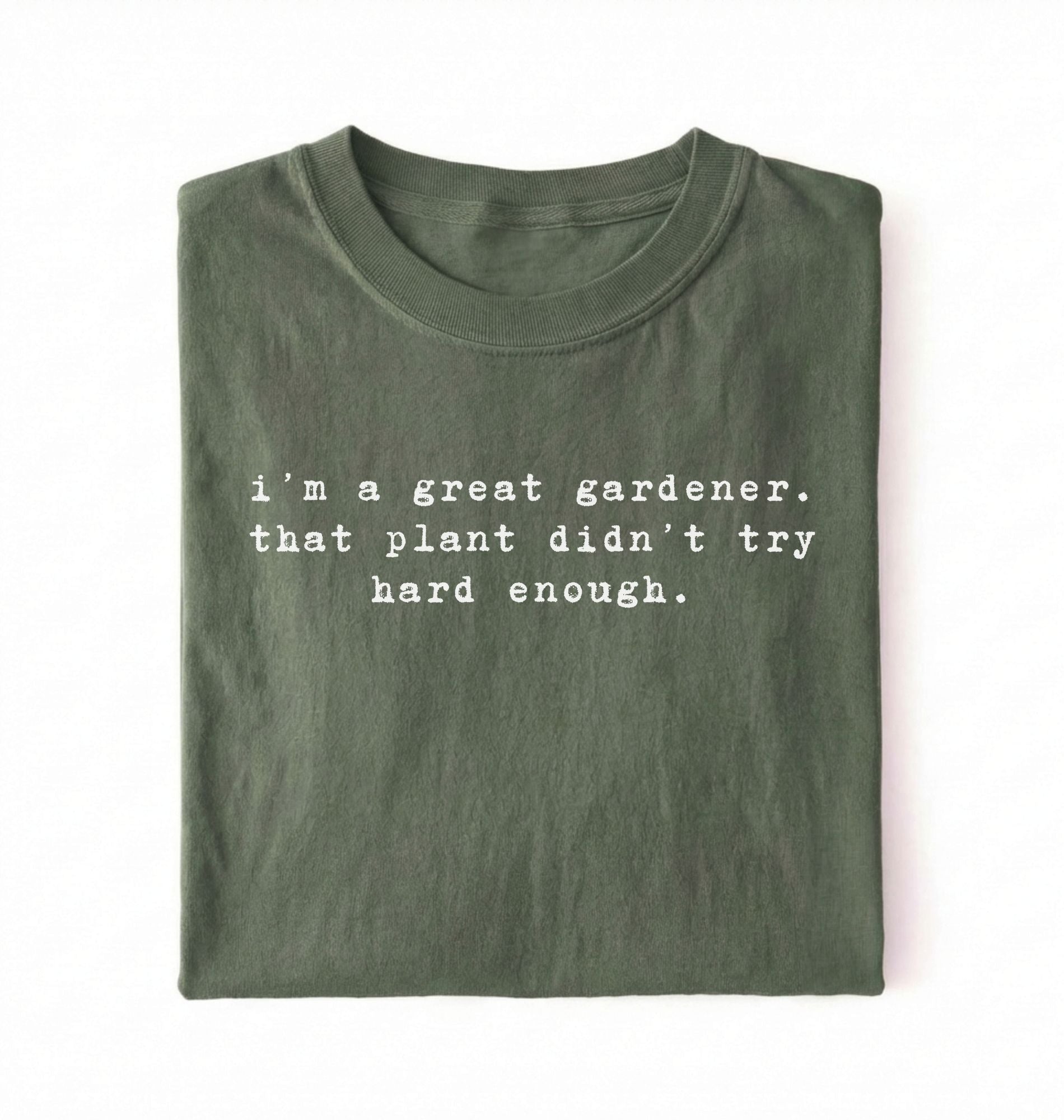 Flat lay of a dark green t-shirt featuring text reading “I’m a great gardener, that plant didn’t try hard enough.” Funny gardening shirt perfect for plant lovers, gardeners and houseplant owners on a white background