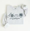 Flat lay of a ash crewneck sweatshirt with line drawings of gardening items and text reading “in my granny era.”