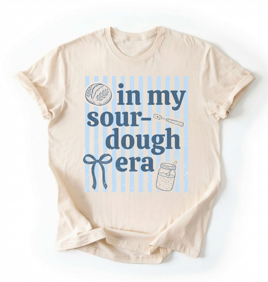 Flat lay of an ivory In my sourdough era shirt with baking icons and stripes perfect gift for sourdough lovers and home bakers on a white background