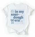 Flat lay of an white In my sourdough era shirt with baking icons and stripes perfect gift for sourdough lovers and home bakers on a white background