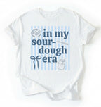 Flat lay of an white In my sourdough era shirt with baking icons and stripes perfect gift for sourdough lovers and home bakers on a white background