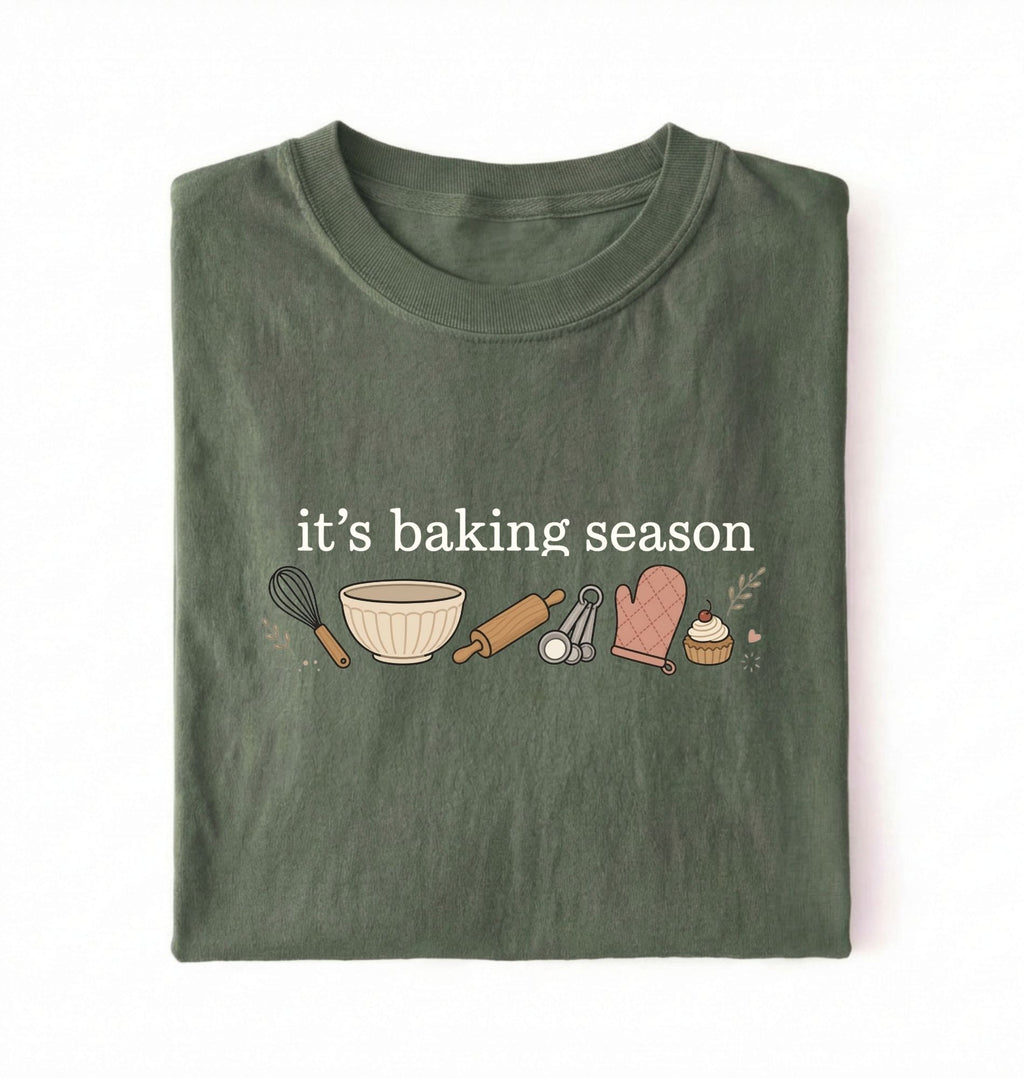 Flat lay of a green its baking season shirt with baking tools cupcake and oven mitt cute baker gift on a white background 