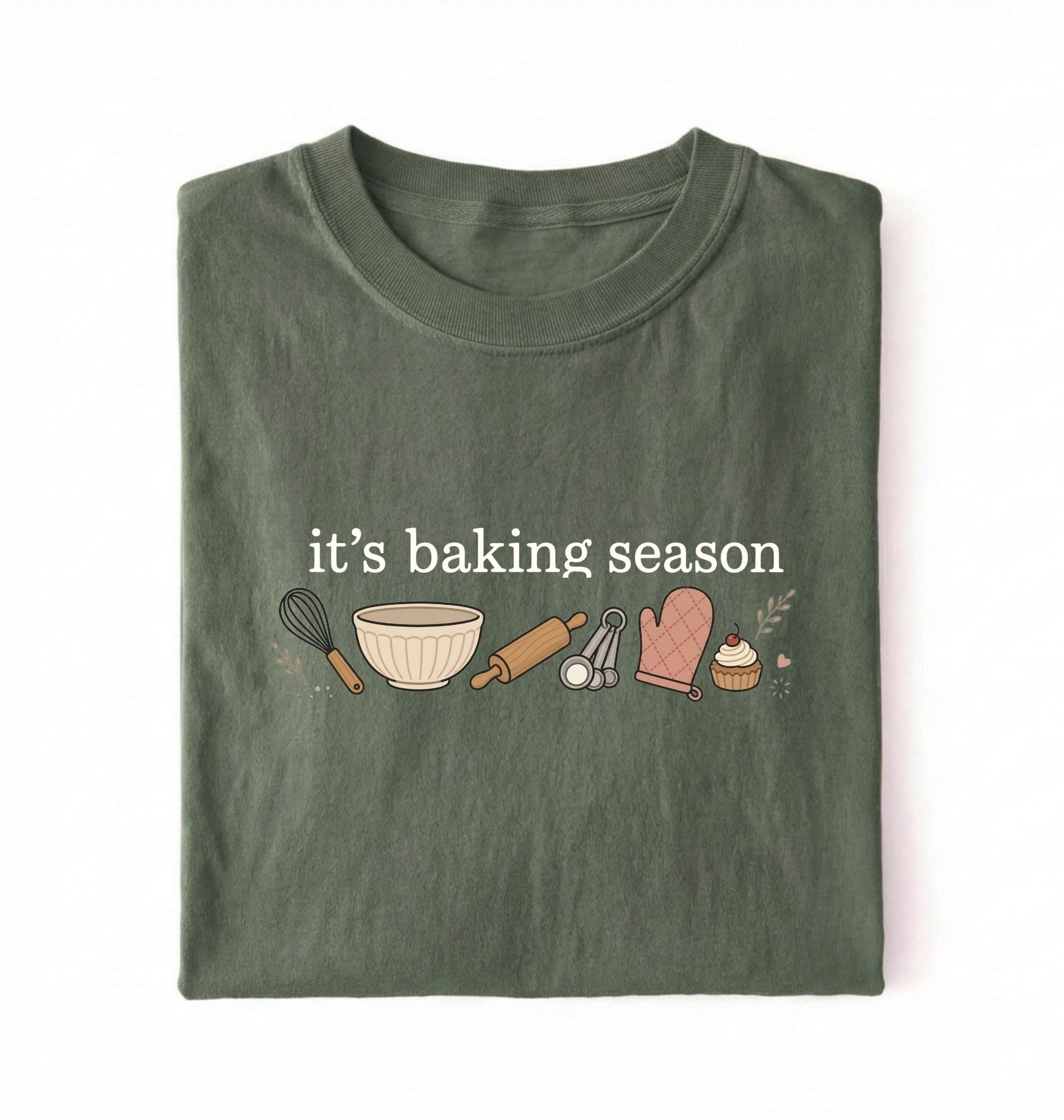 Flat lay of a green its baking season shirt with baking tools cupcake and oven mitt cute baker gift on a white background 