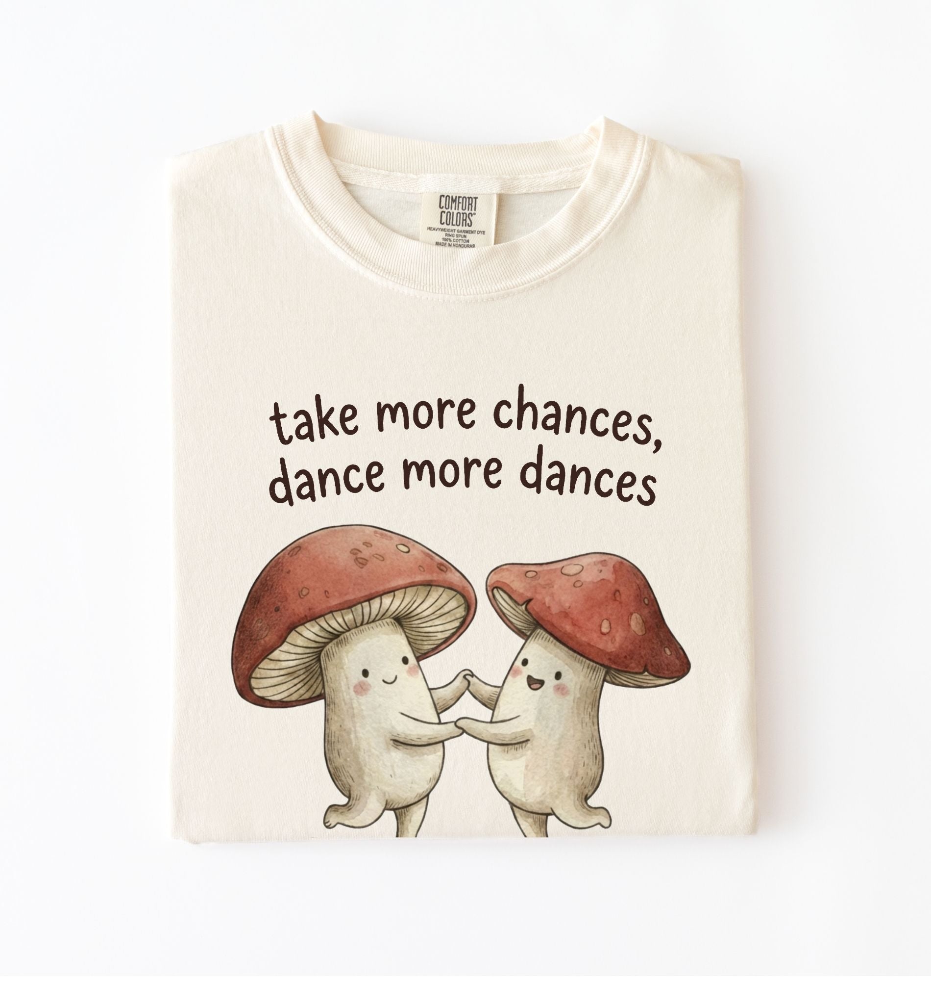 Ivory t-shirt with two dancing mushrooms and the phrase take more chances dance more dances, whimsical cottagecore gift tee