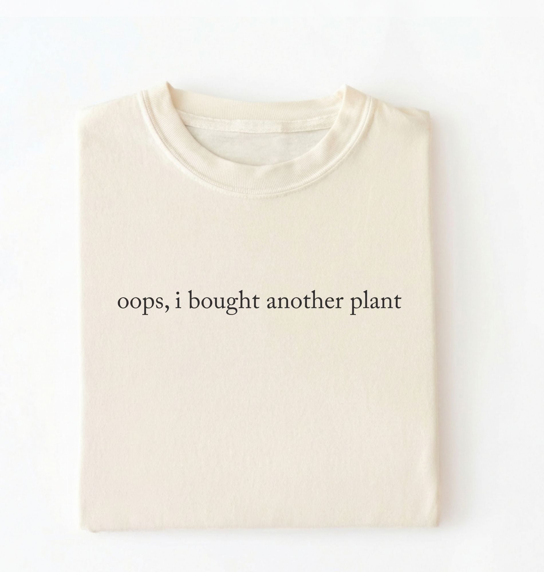 Flat lay ivory t-shirt with 'oops, I bought another plant' with humorous text on a white background