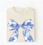 Ivory t-shirt with a white and blue floral bow graphic in a coquette cottagecore aesthetic, perfect as a stylish gift