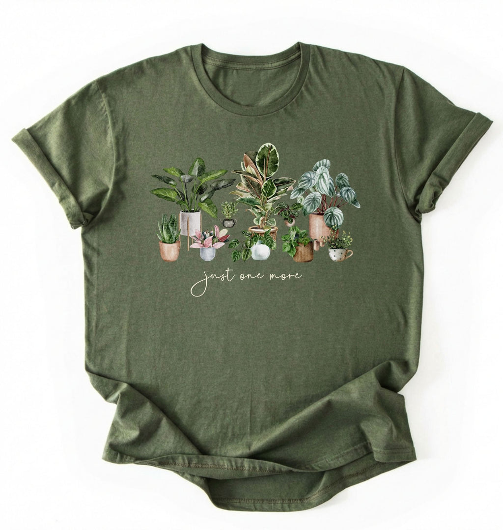 Flat lay of Military Green t-shirt with plant illustrations and 'just one more' text on a white background