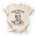 Flat lay of an ivory Kitty Biscuits Bakery shirt featuring a baking kitten and dough on cream t-shirt on  a white background 
