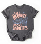 Flat lay of a charcoal less regrets more baguettes shirt brown funny baking t shirt bread lover gift foodie humor design on a white background 