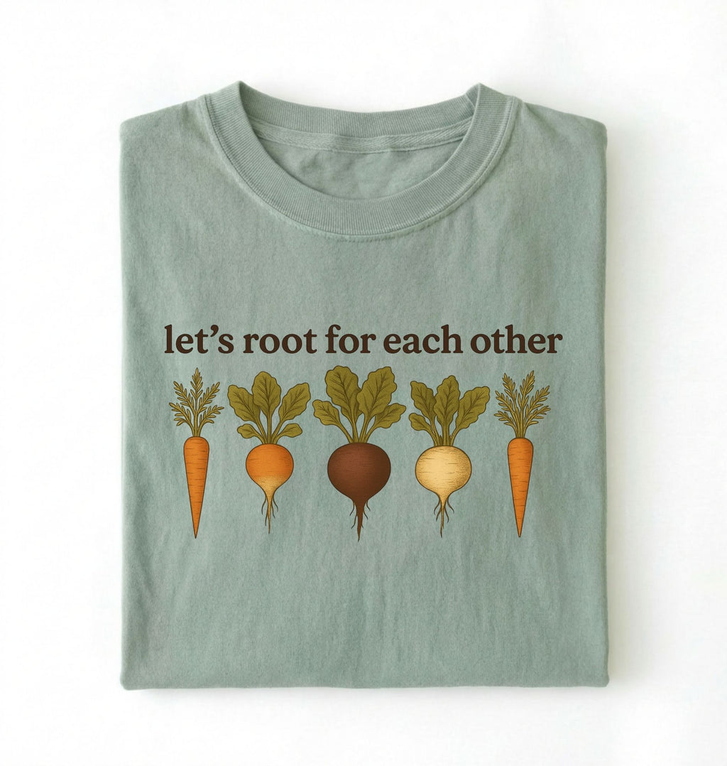 Flat lay of a bay t shirt with the text Let’s root for each other gardening t-shirt with illustrated root vegetables, perfect gardener gift on a white background