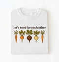 Flat lay of a white t shirt with the text Let’s root for each other gardening t-shirt with illustrated root vegetables, perfect gardener gift on a white background 