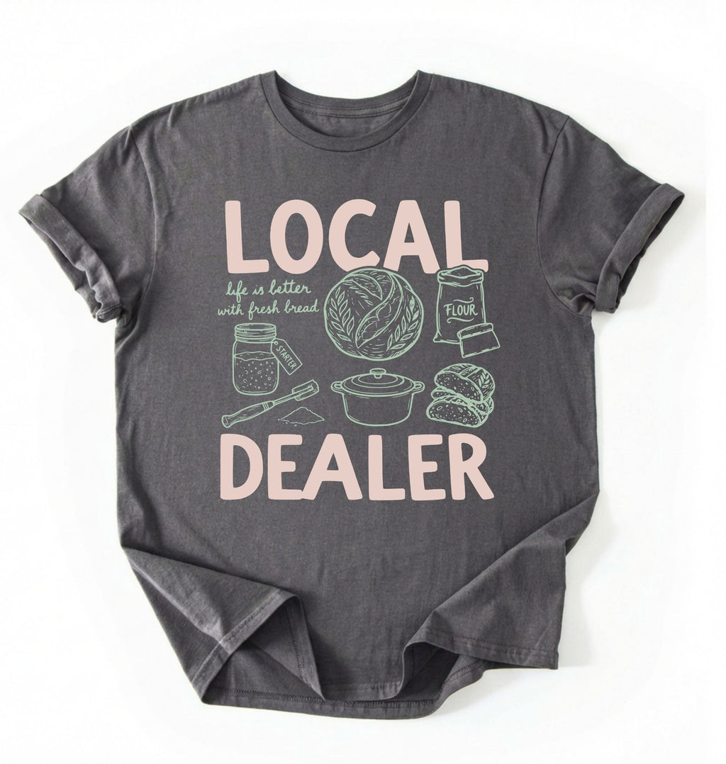 Flat lay of a Charcoal Funny local dealer bread shirt with baking tools and sourdough theme perfect gift for bakers and bread lovers on a white background 